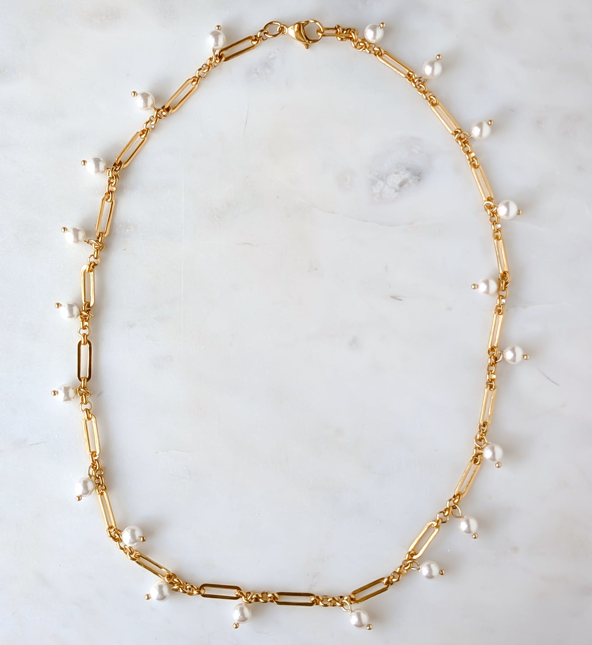 Gold necklace with pearls on a marble surface