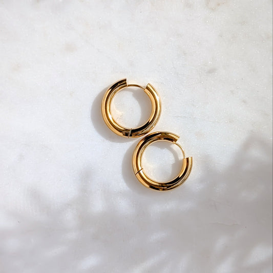 Gold hoop earrings on a textured white surface