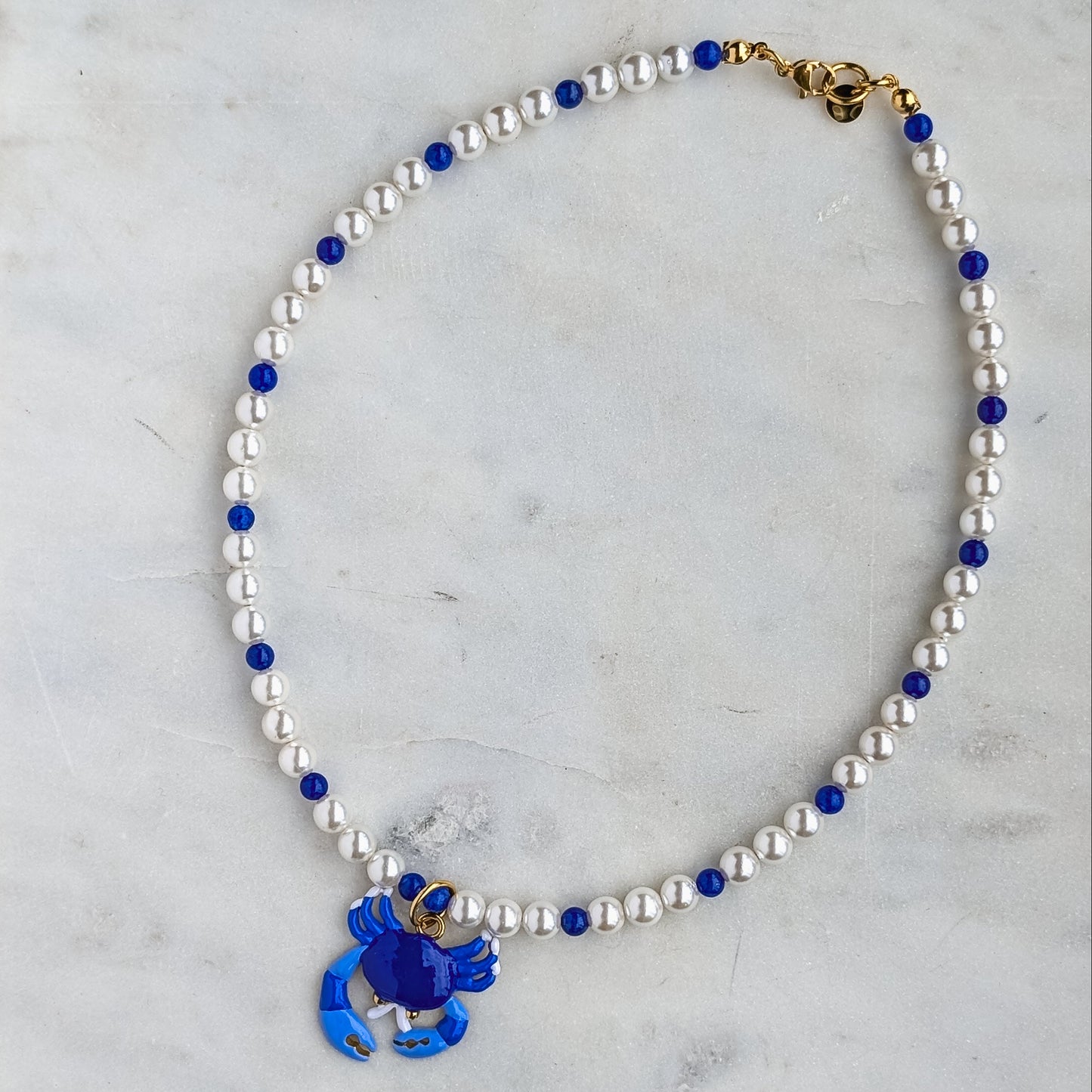 Necklace with blue flower charm on a marble surface